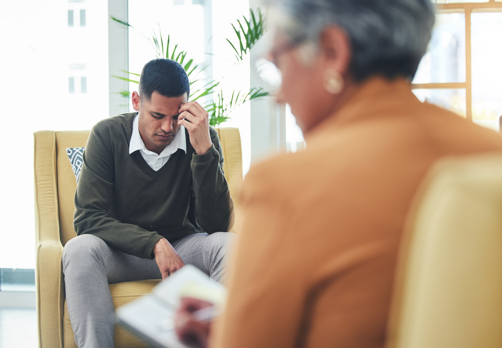 Psychologist notes, man stress and sofa with woman, therapy or listen for mental health, mindset or care. Psychiatrist, patient and frustrated in clinic, book or couch for help, anxiety or depression.