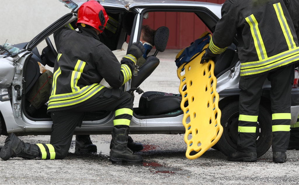 Team of firefighters on the road after the crash and the yellow stretcher
