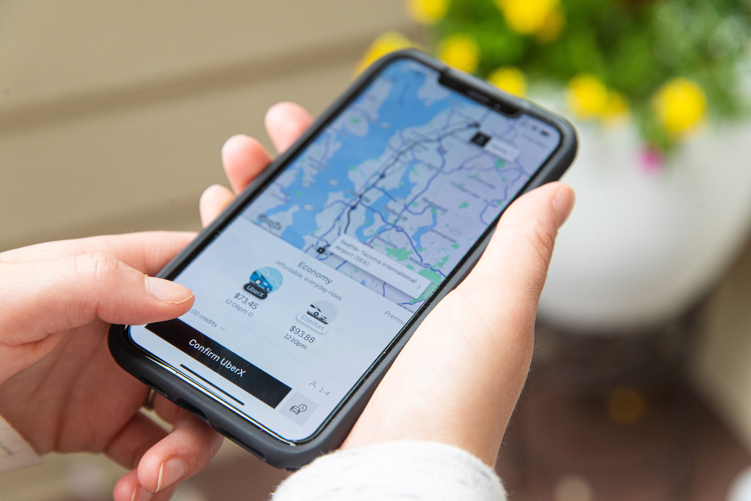Hands hold iPhone XS Max while viewing Uber application in Evere